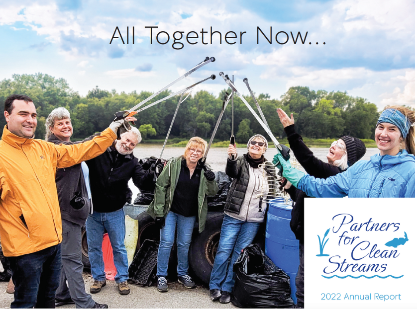 2022 Annual Report Cover. A group of volunteers stands in front of the Maumee River with their grabbers held aloft. The text above them reads "All Together Now..."