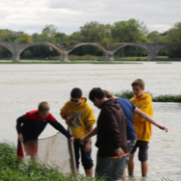 Student volunteers with TMACOG use a macroinvertebrate sampling net as a tool for water quality monitoring.