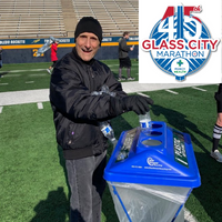 A smiling volunteer sorts recycling at the 2019 Glass City Marathon.