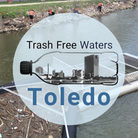 Trash Free Waters Toledo logo overtop of a "Brute Bin" trash trap device in Swan Creek, Toledo, Ohio.