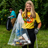 A photo of a volunteer holding up a clear trash bag of removed marine debris.